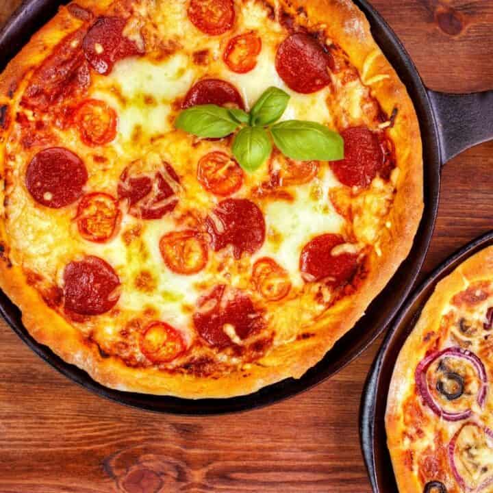 two homemade pizzas in cast iron skillets