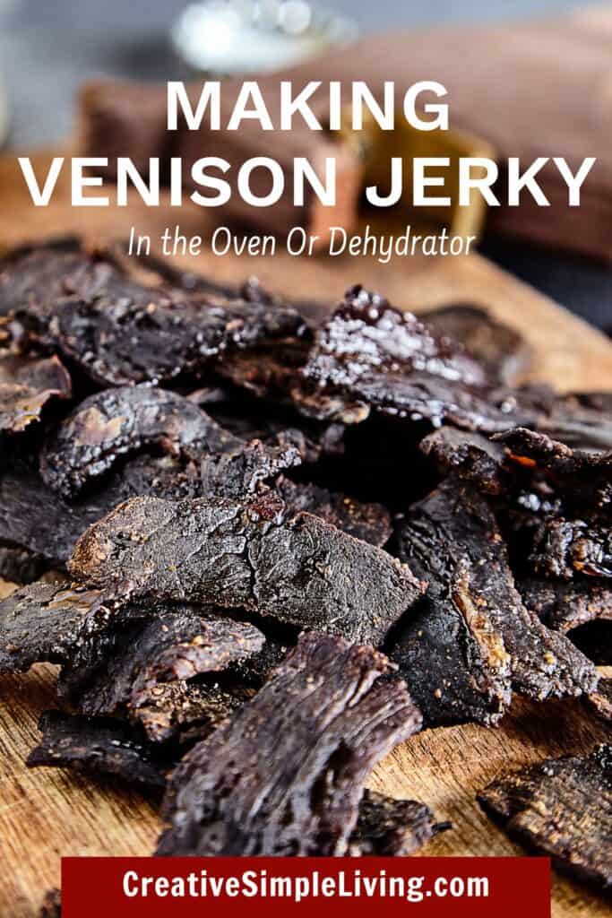 Close-up of dark brown venison jerky pieces on a wooden board, with white text overlay reading "Making Venison Jerky In the Oven or Dehydrator" and a website link at the bottom.