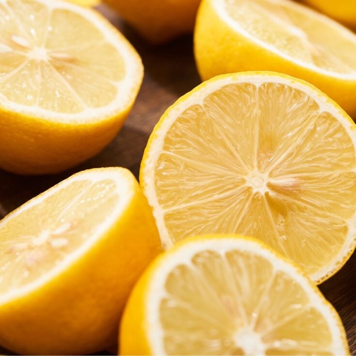 Close-up of several fresh lemons cut in half, showing their juicy, bright yellow interior and textured rind. The image is well-lit, highlighting the details and freshness—perfect for freezing lemons or enjoying as frozen lemons.