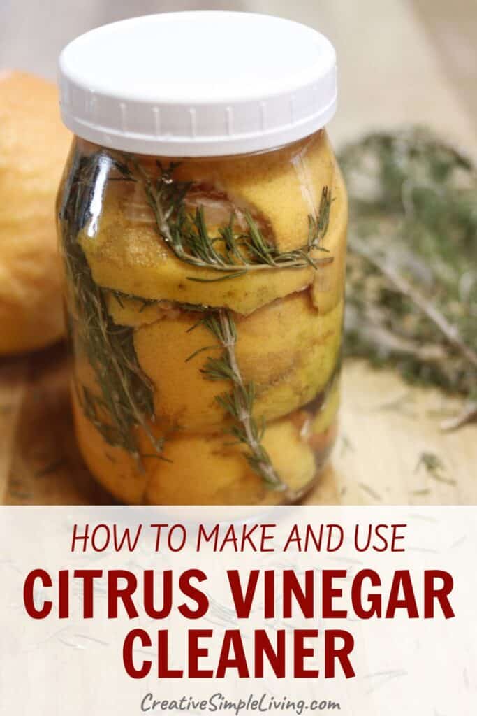 A glass jar filled with citrus peels and sprigs of herbs, likely rosemary, sits on a wooden surface next to fresh herbs. Text reads: "How to make and use citrus vinegar cleaner. CreativeSimpleLiving.com.