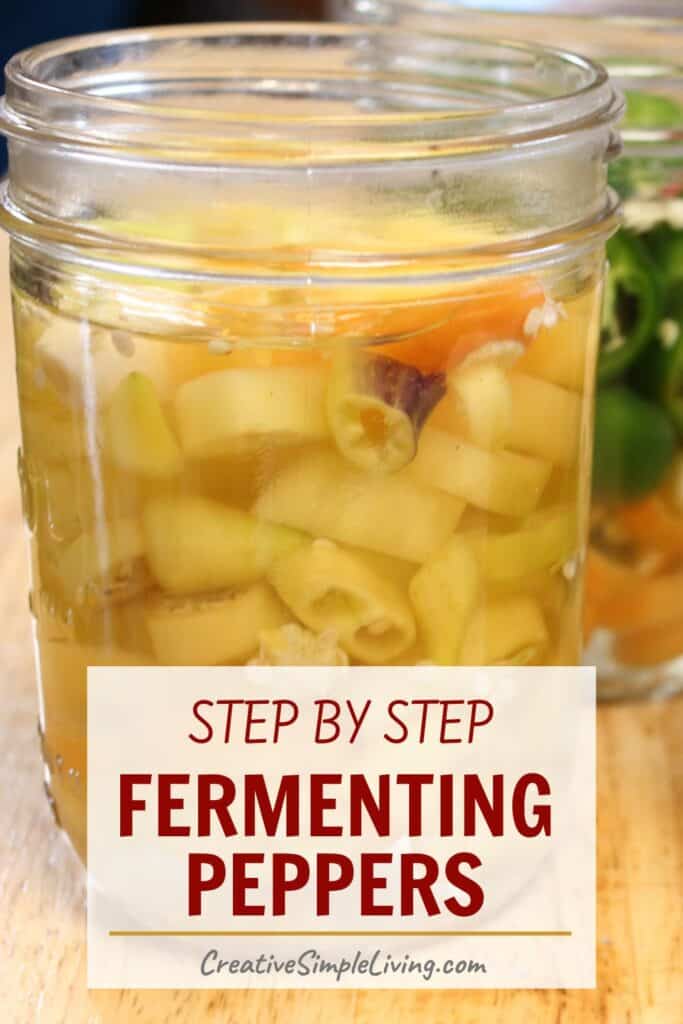 A close-up of a glass jar filled with fermented peppers in liquid, shown next to another jar with green peppers. Text overlay reads: "Step by step fermenting peppers, CreativeSimpleLiving.com.