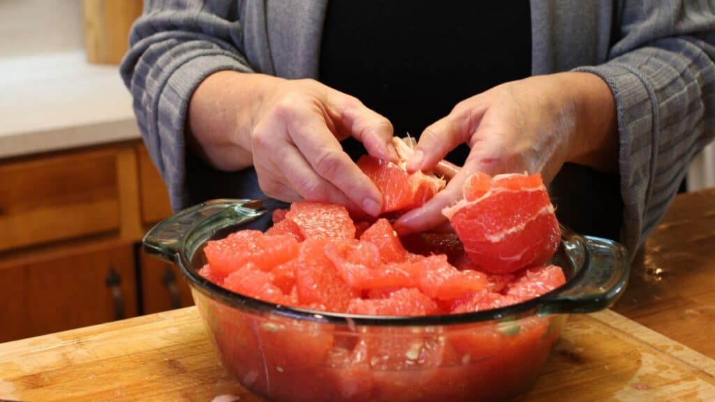 a woman segmenting a grapefruit