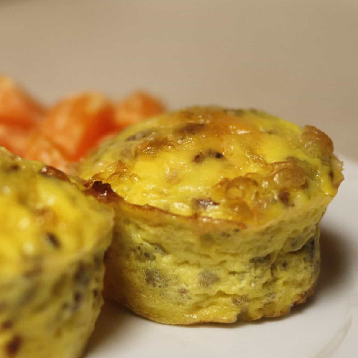 egg muffins on a white plate with oranges in the background