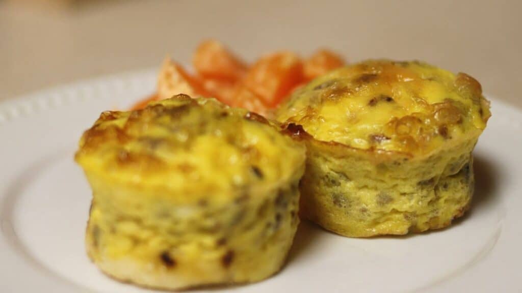 egg muffins on a white plate with oranges in the background