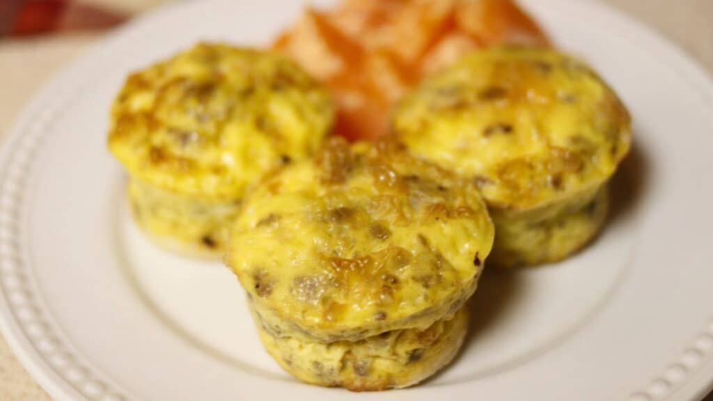 egg muffins on a white plate with oranges in the background