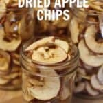 Three glass jars filled with homemade dried apple chips, showcasing thinly sliced apples with red peels. Text overlay reads “Homemade Dried Apple Chips”—a delicious result of dehydrating apples at home.