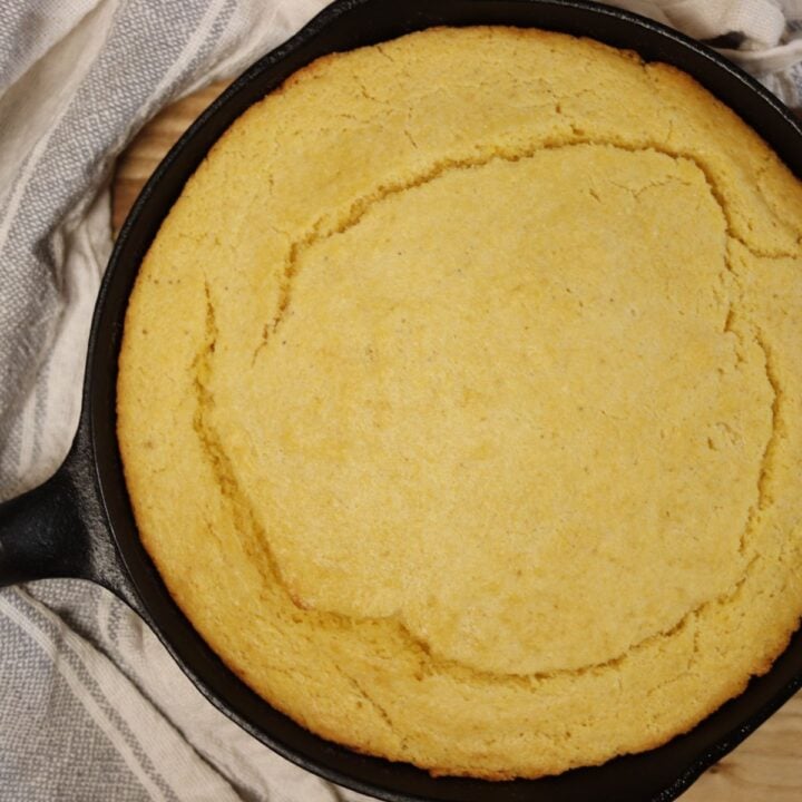 Overhead view of cornbread baked in a cast-iron skillet.