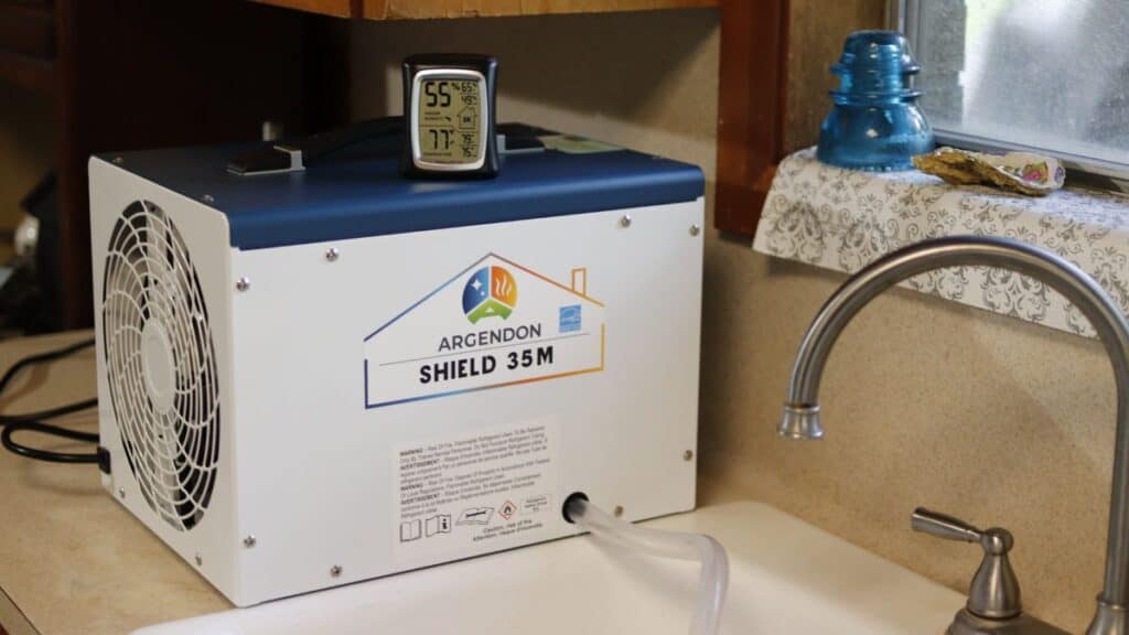 Argendon Shield 35M dehumidifier sitting on a kitchen counter next to a sink with a digital hygrometer on top.